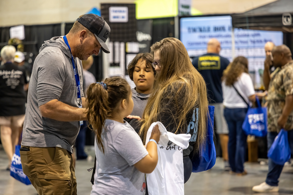 A family sorts through show swag together, a sweet parenting moment on the floor of the Florida Saltwater Fishing Expo.