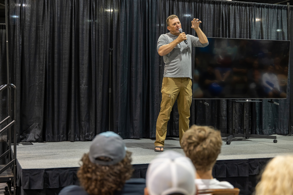 A guest speaker gestures mid-story on stage in front of an attentive crowd at the Florida Saltwater Fishing Expo.