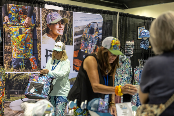 Shoppers browse Fishe's colorful fish-print apparel and coolers at the Florida Saltwater Fishing Expo.