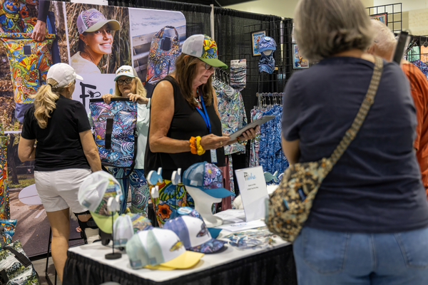 Shoppers try on Fishe's colorful trucker hats at their apparel booth at the Florida Saltwater Fishing Expo.