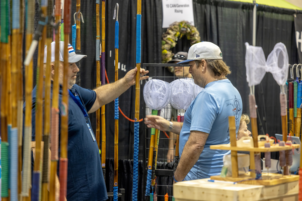 Attendees examine handcrafted bamboo rod blanks and landing nets at a custom rod builder's booth at the Florida Saltwater Fishing Expo.