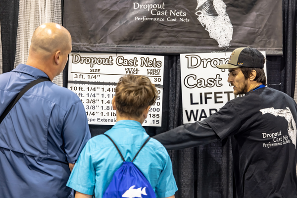 A Dropout Cast Nets rep walks a father and son through cast net pricing and lifetime warranty details at the Florida Saltwater Fishing Expo.