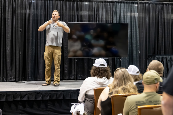 A seminar speaker in a Hunt. Fish. Eat Meat. tee addresses the crowd with a video presentation at the Florida Saltwater Fishing Expo.