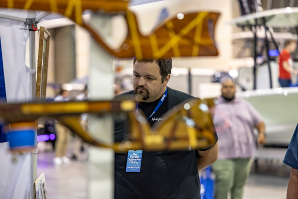 A vendor studies a rack of custom wooden gaffs on display at his booth at the Florida Saltwater Fishing Expo.