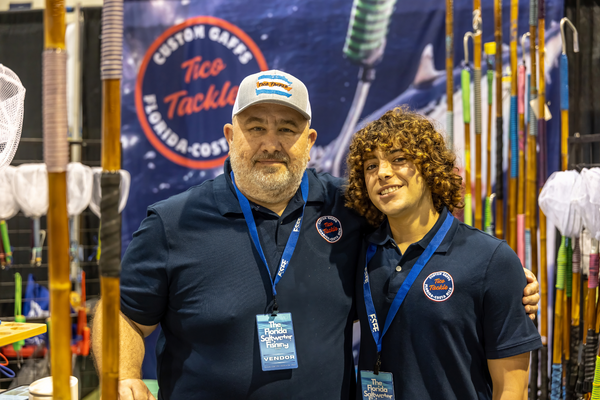 A father-and-son team from Tico Tackle poses in front of their custom gaff display at the Florida Saltwater Fishing Expo.