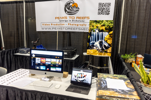 The Peaks to Reefs Media booth showcases video production and photography work on an iMac at the Florida Saltwater Fishing Expo.