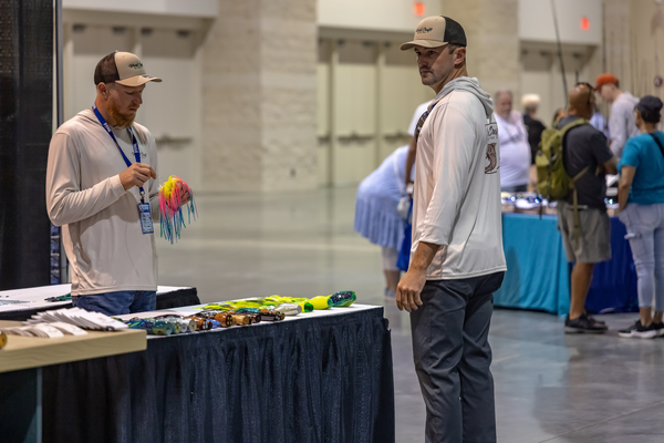 Wood Craft Marine team members inspect handmade trolling lures at their table at the Florida Saltwater Fishing Expo.