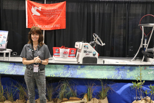 Shoppers browse racks of fishing apparel, including Bare Huntress gear, at a busy vendor booth during the Florida Fishing Expo.