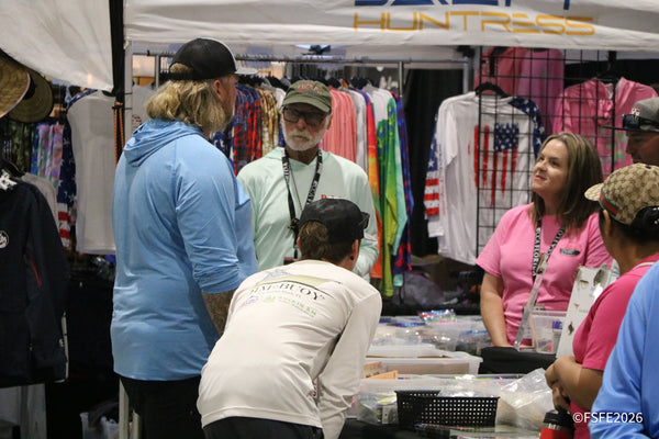 A Sea Spirit Deep Sea Fishing team member laughs with two kids at the prize wheel, part of the family fun at the Florida Fishing Expo.