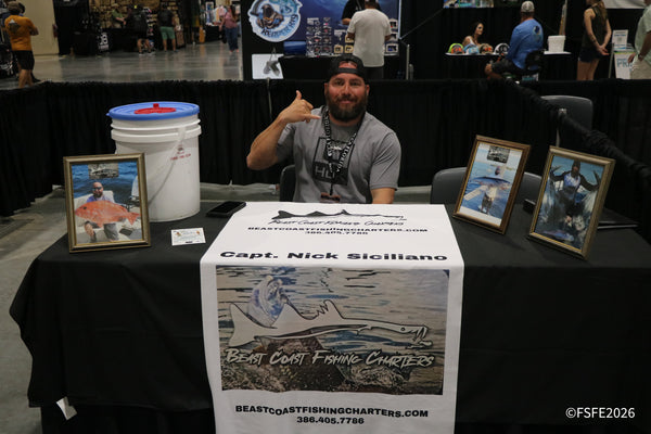 Capt. Nick Siciliano of Beast Coast Fishing Charters throws a shaka behind a table of framed catch photos at the Florida Fishing Expo.