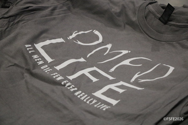 A close-up look at an Omen Life graphic tee for sale among the apparel booths at the Florida Fishing Expo.