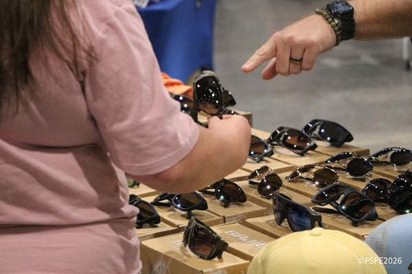 A shopper tries on a pair of Bajio sunglasses at the Florida Fishing Expo's eyewear display.