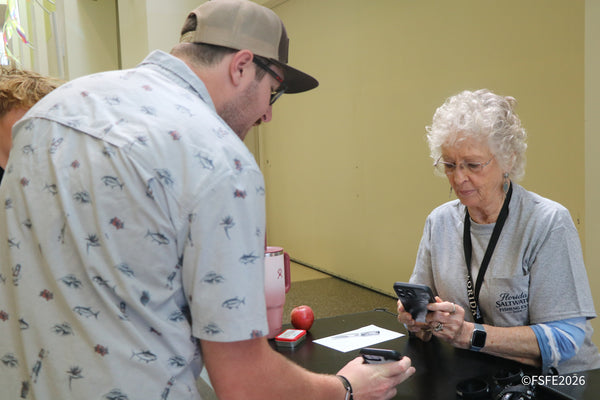 A volunteer helps an attendee check in at the registration table during the Florida Fishing Expo.