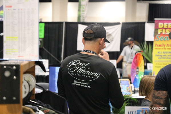 An attendee in a Reel Harmony Fishing Charters shirt browses the aisles at the Florida Fishing Expo.
