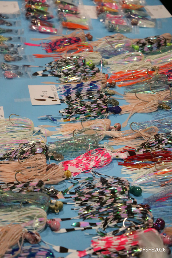 Rows of colorful handmade trolling jigs and skirts laid out for sale at the Florida Fishing Expo.