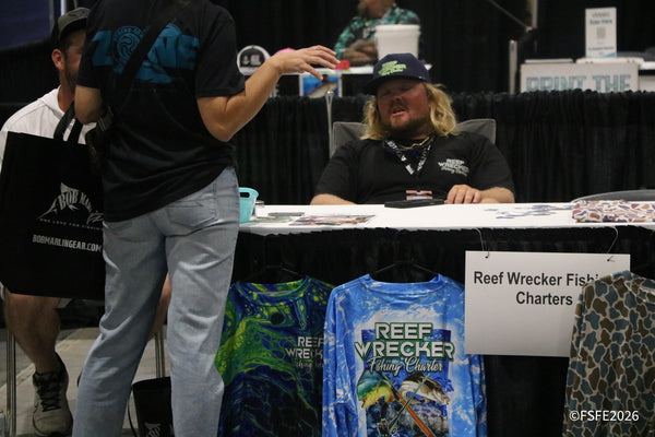 An attendee carrying a Bob Marlin Gear bag chats with the Reef Wrecker Fishing Charters crew at the Florida Fishing Expo.