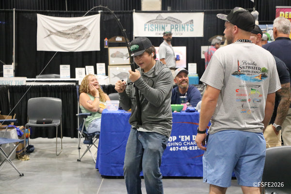A teen practices his cast as a nearby vendor bursts out laughing near the Fishin' Prints booth at the Florida Fishing Expo.