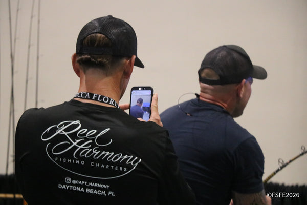 A captain in a Reel Harmony Fishing Charters shirt snaps a photo at the Florida Fishing Expo, repping his Daytona Beach charter business.