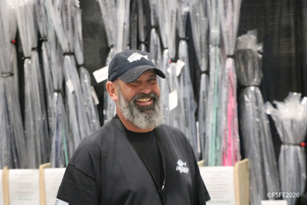 A vendor shares a big laugh in front of a wall of trolling lures at the Florida Fishing Expo.
