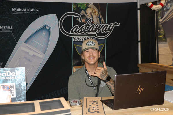 A Castaway Customs vendor grins and throws a shaka sign in front of his custom boat deck display at the Florida Fishing Expo.