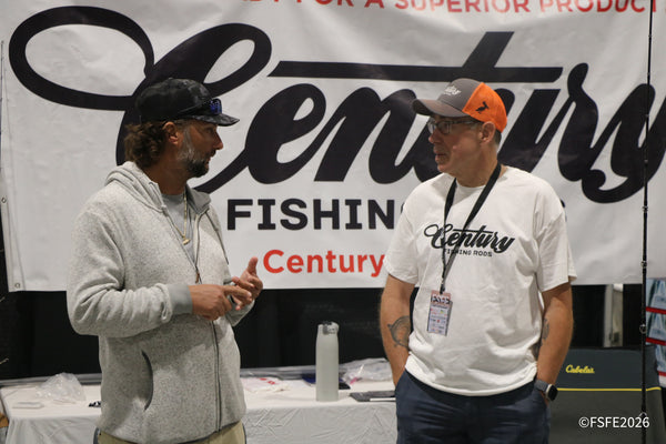 Two attendees chat in front of the Century Fishing Rods banner at the Florida Fishing Expo.