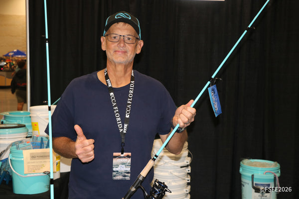 A Lee Fisher Sports rep gives a thumbs-up while holding a teal rod at his Florida Fishing Expo booth.