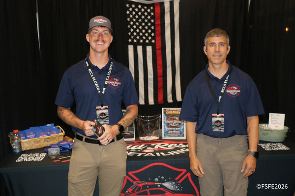 Two grinning Rapid Rescue Detailing team members pose in front of a giveaway display at the Florida Fishing Expo.