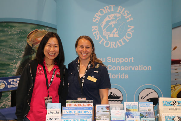 Two smiling Sport Fish Restoration and Florida Fish and Wildlife representatives welcome visitors at the Florida Fishing Expo.