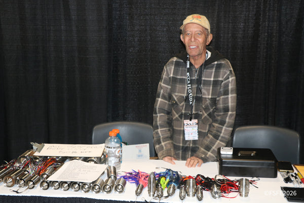 A smiling vendor stands behind his handmade trolling lures and cowbell rigs at the Florida Fishing Expo.