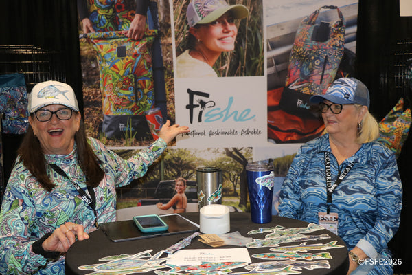 Two laughing Fishe brand reps show off their colorful fishing apparel and gear at the Florida Fishing Expo.