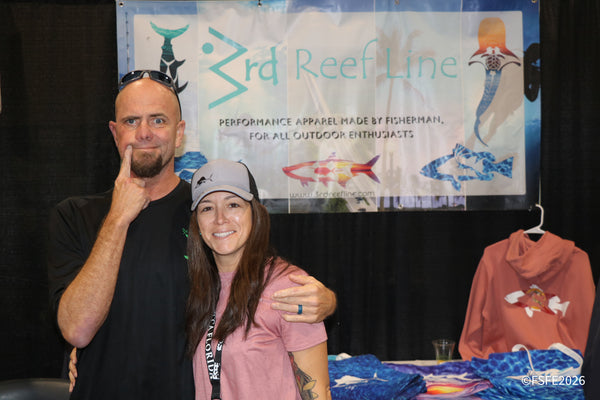 A playful couple poses in front of the 3rd Reef Line performance apparel banner at the Florida Fishing Expo.