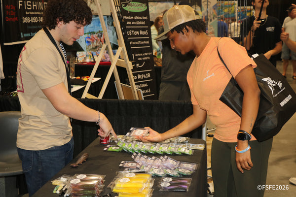 A Dragonfly Tackle Company vendor helps a shopper pick out soft plastic lures at the Florida Fishing Expo.