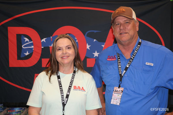 A smiling couple reps D.O.A. Fishing Lures, "The Unfair Advantage," at their Florida Fishing Expo booth.