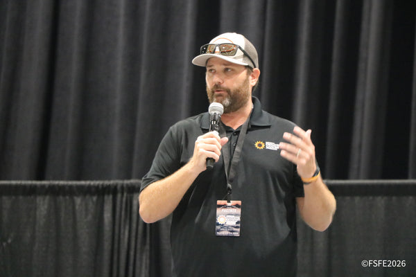 A speaker addresses the crowd on stage, representing the National Pediatric Cancer Foundation as a Florida Fishing Expo partner.