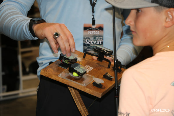 A Blind Cast vendor demonstrates his adaptive fly-tying device to an attentive young visitor at the Florida Fishing Expo.