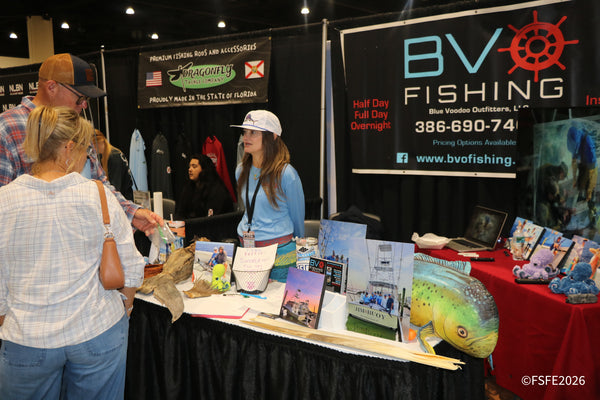 A BVO Fishing (Blue Voodoo Outfitters) rep chats with visitors beside a Dragonfly Tackle Company display at the Florida Fishing Expo.