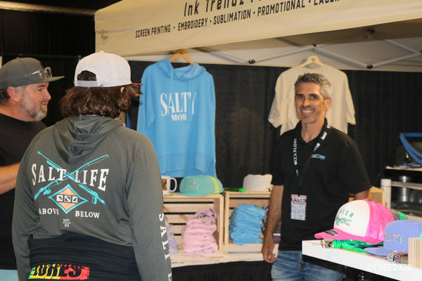 Shoppers browse Salty Mom hoodies and hats at the Ink Trendz screen printing booth during the Florida Fishing Expo.