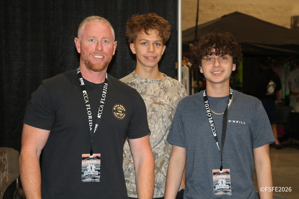 Three generations of an Outdoor Trader vendor team, one sporting a Sitka Gear shirt, smile together at the Florida Fishing Expo.