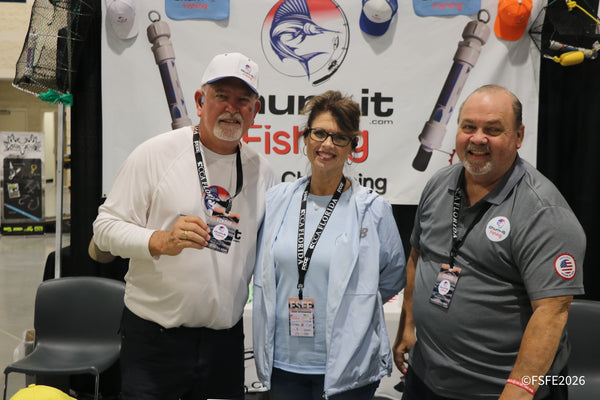 The Chum-It Fishing crew smiles together at their branded booth during the Florida Fishing Expo.