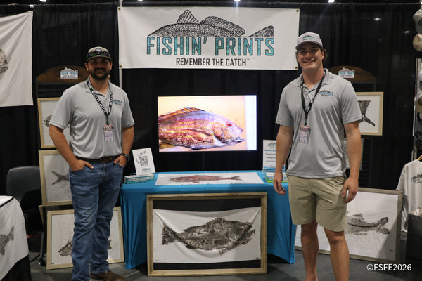 Two Fishin' Prints team members smile in front of their 'Remember the Catch' gyotaku fish print display at the Florida Fishing Expo.