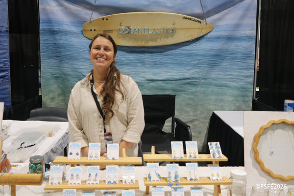 A smiling Ocean Plastics artisan shows off handmade jewelry crafted from recycled ocean plastic at the Florida Fishing Expo.