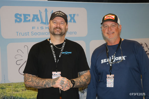 Two smiling SeaWorx Fishing team members pose at their booth, "Trust SeaWorx," at the Florida Fishing Expo.