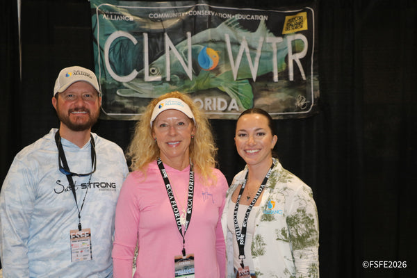 Three smiling volunteers from Salt Strong and the Clean Water Florida Alliance pose together at their conservation booth during the Florida Fishing Expo.