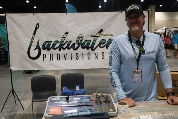A Backwater Provisions Co. rep smiles beside his fillet knife lineup at the Florida Fishing Expo.
