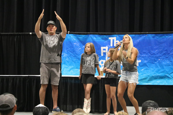 The DMFD Life family fires up the crowd on stage, arms raised and mic in hand, at the Florida Fishing Expo.
