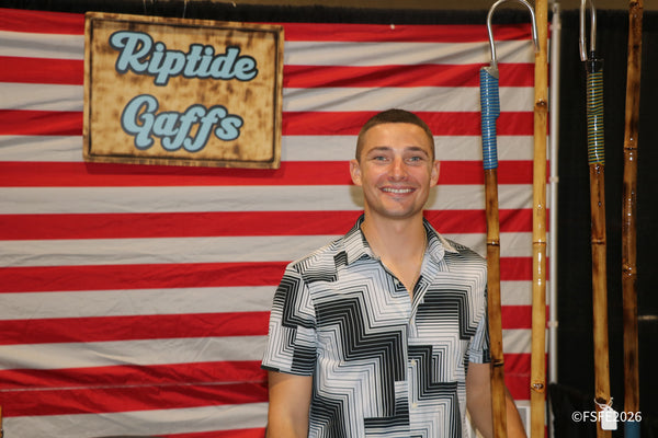 A Riptide Gaffs team member smiles in front of the brand's handcrafted bamboo gaffs at the Florida Fishing Expo.