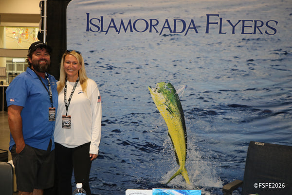 A smiling couple from Islamorada Flyers poses in front of a mahi-mahi mural at the Florida Fishing Expo.