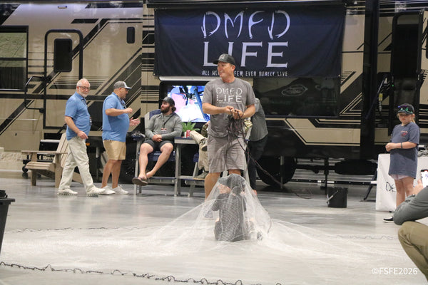 A DMFD Life demonstrator fans out a cast net mid-throw as onlookers watch and laugh at the Florida Fishing Expo.